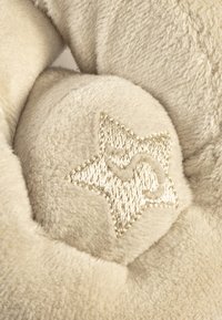Cream plush star-shaped cushion with soft texture and gold embroidery. Features rounded edges and a distinct star pattern detail.