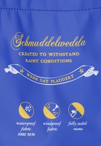 Mėlynas vandeniui atsparus audinys su auksine tekstūra ir ikonėlėmis. Tekstuose nurodyta "Schmuddelwedda", "sukurtas atlaikyti lietingas sąlygas" ir priežiūros instrukcijos.
