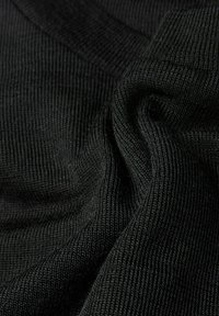 Schwarzer Strickstoff mit einer feinen, gerippten Textur, die Falten und Konturen zeigt und die Weichheit und Dehnbarkeit des Materials hervorhebt.