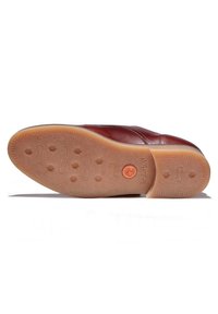 Chaussure en cuir avec semelle en caoutchouc marron clair présentant le logo Timberland et un motif de bande de roulement, vue de dessous sur fond blanc.