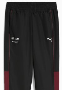Sorte letvægts sportbukser med maroon sidepaneler. Har en elastisk talje, lommer og logoer: BMW Motorsport og Puma.