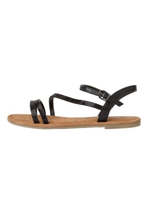 Sort flad sandal med tynde teksturerede stropper, ankelspænde og brun polstret sål vist i sideprofil mod hvid baggrund.