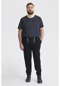 Pantalons noirs avec des poignets élastiques, une taille à cordon de serrage et des poches latérales, associés à un t-shirt ajusté bleu marine avec une poche poitrine.