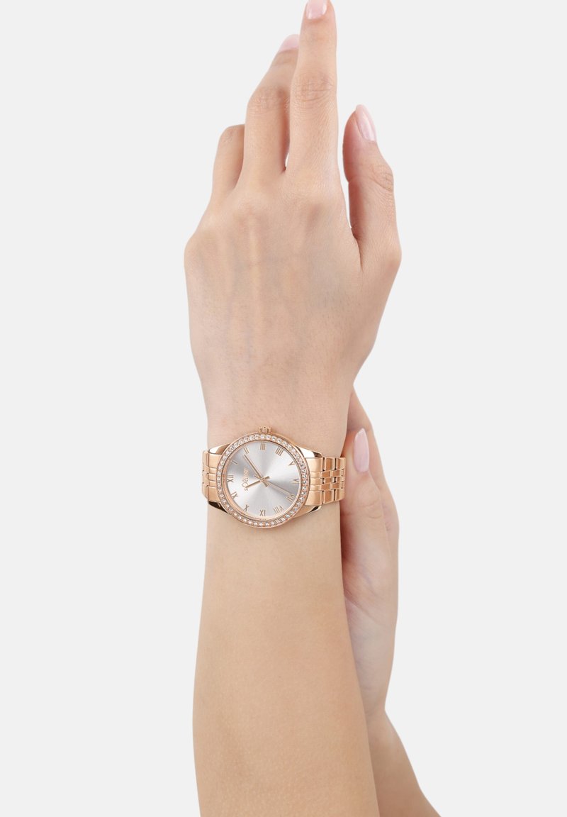 Roségoldene Armbanduhr mit rundem Ziffernblatt, silbernem Zifferblatt, römischen Ziffern und einem diamantähnlich besetzten Lünette. Metallgliederarmband.