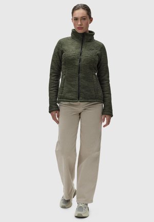 Olive green fleece jacket with a high collar and a front zipper. Paired with beige wide-leg trousers and light-colored sneakers.