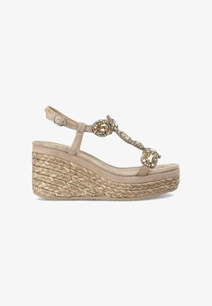 Beige wedge sandaal met een espadrille-achtige jute zool, voorzien van een decoratieve band met heldere en gouden versieringen.