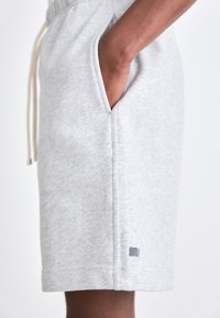 Gray cotton blend shorts with an elastic waistband and drawstring, featuring side pockets and a small navy logo detail on the hem.