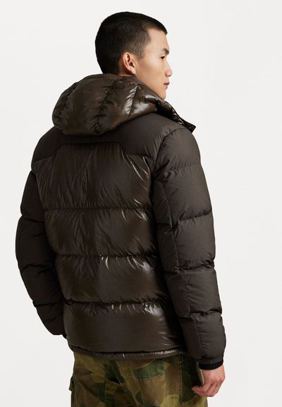 Dark brown puffer jacket with a shiny finish, featuring a hood, quilted texture, and elastic cuffs. Worn with camouflage pants.