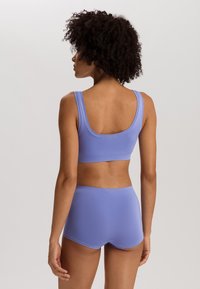 Ljust lila sport-bh och matchande shorty, tillverkad av mjukt, elastiskt material. Designen har breda band och sömlösa kanter.