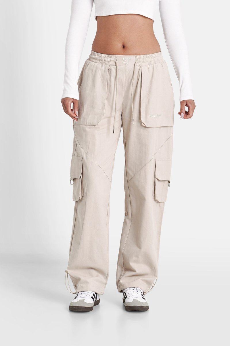Beige cargobroek met een wijde pasvorm, voorzien van meerdere zakken, een koordansluiting en contrasterende stikdetails.