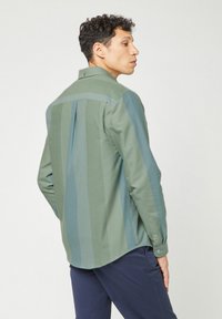 Grüne Hemdbluse mit vertikalen Streifen in verschiedenen Schattierungen, aus einem weichen Stoff mit einem Rückenfalten und einem Button-Down-Kragen.