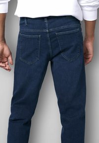 Dunkelblaue Denim-Jeans mit geradem Schnitt, ausgestattet mit zwei Gesäßtaschen mit schrägen Klappen und sichtbaren Nähdetails. Glatte Textur.
