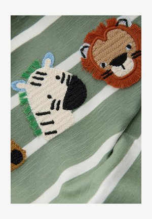 Zelená bavlněná látka s bílými pruhy obsahuje vyšité tváře zvířat: zebra se zelenými akcenty a lev s oranžovými a hnědými texturami.