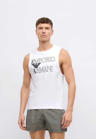 Biały, bezrękawnik z logo "Emporio Armani" w czerni, zestawiony z czarno-białymi pasiastymi szortami. Gładka tkanina i luźny krój.