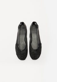 Black flat shoes made of smooth material, featuring textured floral accents on the toe and a rounded design without distinct hardware details.