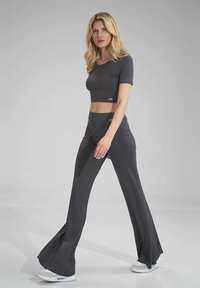 Szary crop top z krótkimi rękawami w połączeniu z do talii wysokimi spodniami w kolorze szarym z szerokimi nogawkami. Tkanina jest gładka z delikatnym połyskiem, zaprojektowana z myślą o komforcie.