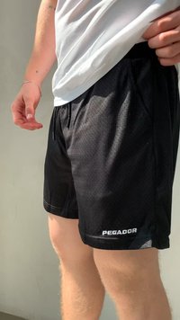 Čierne športové šortky vyrobené z priedušnej sieťoviny, so šnúrkou v pase a logom "PEGADOR" v bielej farbe na spodnej strane.