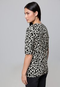 Tričko s leopardím potiskem v světle béžové barvě s černými skvrnami. Krátké rukávy, kulatý výstřih, volnější střih, vyrobeno z měkké látky.