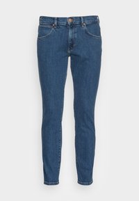 Indigo blå smala jeans i denimmaterial, med knappstängning, fem fickor och subtila sömnadsdetaljer. Slät textur.