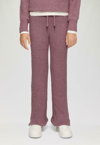 Paarse textuurbroek met een losse pasvorm en een tailleband met trekkoord, gecombineerd met witte schoenen. De stof lijkt zacht en comfortabel te zijn.