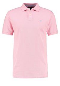 Polo rose clair en tissu texturé ; doté d'un col, de deux boutons et d'un petit logo bleu sur le côté gauche de la poitrine. Manches courtes.