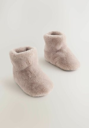 Botine bej pufoase, cu o textură moale, vârf rotunjit și un design cu manșetă pliabilă, destinate purtării în interior.