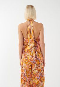 Halter-neck jurk met een kleurrijke bloemen-paisleypatroon in tinten van oranje, roze en bruin, gemaakt van lichtgewicht stof.