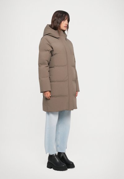 Brown puffer coat with a hood, featuring a quilted design and a relaxed fit. Paired with light blue denim and black chunky boots.