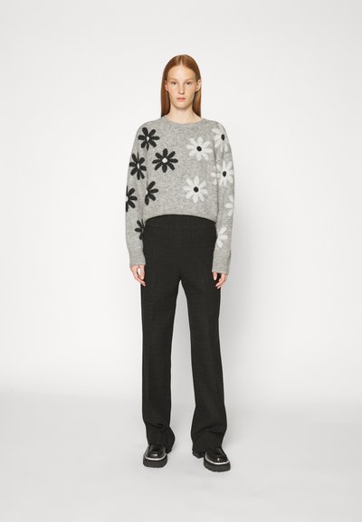 Grå uldtrøje med sort og hvid blomsterprint; parret med sorte, skræddersyede, højtaljede bukser og sorte platformssko.