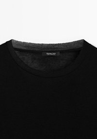 Sort T-shirt med rund hals og grå inderkant ved halsen samt en etiket i kraven med teksten "Massimo Dutti Made in Portugal".