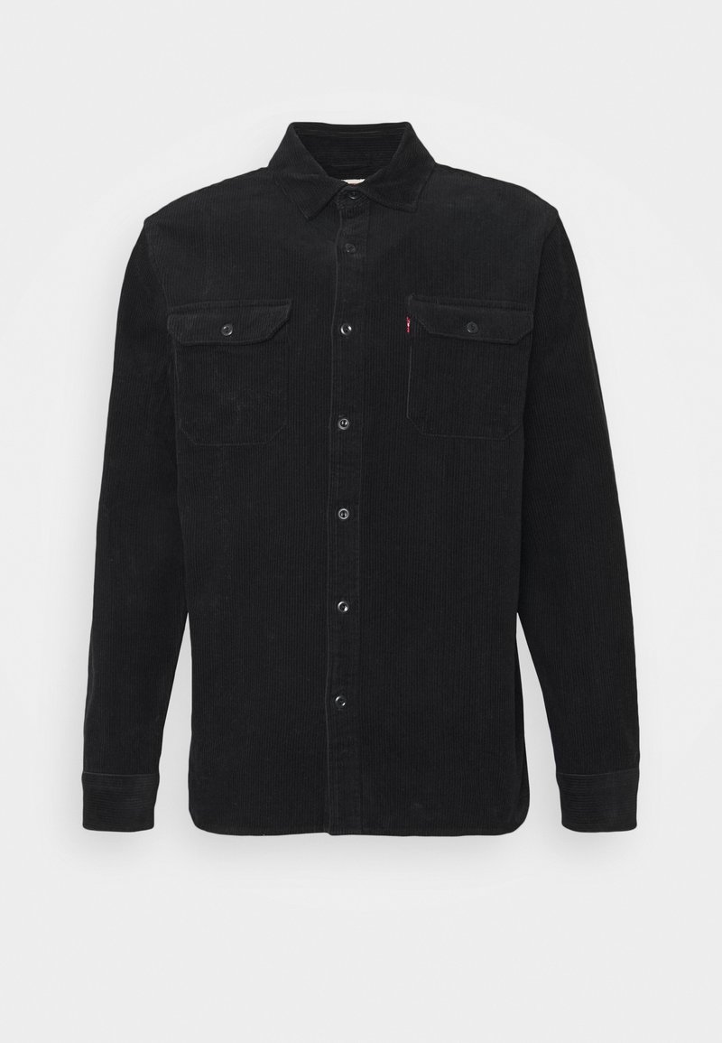 Camisa de pana negra con collar tipo botón, mangas largas, dos bolsillos en el pecho y una textura sutil; cuenta con botones negros y una pequeña etiqueta de logo.
