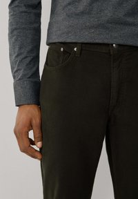 Chinos de algodón verde oscuro con un ajuste slim, que cuentan con dos bolsillos frontales, detalles de costura sutiles y un brillo tenue.