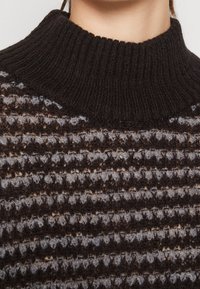 Maglione a maglia nero e grigio con collo alto a coste e un motivo testurizzato con strisce orizzontali alternate. Tessuto morbido e stratificato.