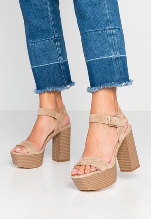 Beżowe sandały na platformie z zamszowej cholewki, szerokimi paskami i kwadratowym obcasem o fakturze w żebrowany wzór.