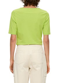 Felgroen T-shirt met korte mouwen en een relaxte pasvorm, voorzien van een ronde halslijn, gecombineerd met beige cargopants met achterzakken en cargovakken.