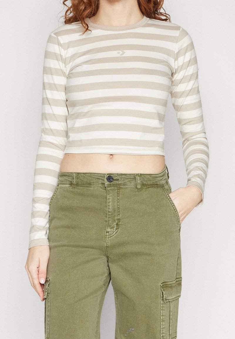 Long-sleeve, cropped top in beige with white horizontal stripes. Features a round neckline and a small logo on the chest. Soft fabric.