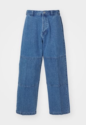 Pantaloni in denim blu chiaro con vestibilità rilassata, dotati di due pannelli in tessuto distinti, chiusura frontale con bottone e gamba ampia.