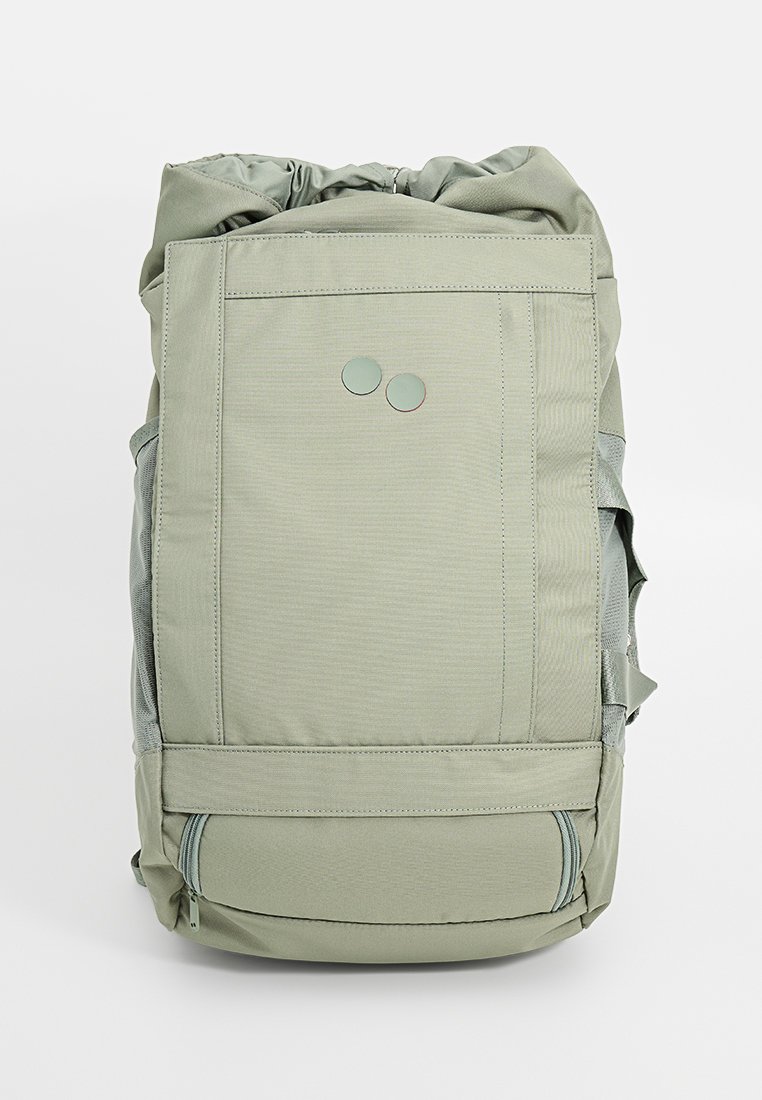 Hellgrüner Rucksack mit Rollverschluss, strukturiertem Stoff, zwei runden Hardware-Akzenten und seitlichen Netzfächern.