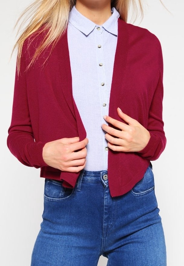 Burgundy cardigan made of soft knit, open front design, long sleeves. Worn over a light blue collared shirt with button details and denim jeans.