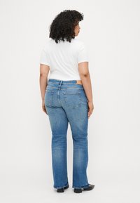 Μπλε τζιν παντελόνι με ίσια γραμμή, μέση μέσου ύψους και δύο πίσω τσέπες. Συνδυασμένο με λευκό πουκάμισο κοντομάνικο.