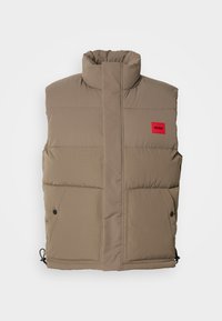 Light brown padded sleeveless vest with high collar, front pockets with buttons, and a small red "HUGO" logo on the chest.