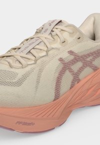 Ανοιχτό μπεζ παπούτσι τρεξίματος Asics με ροζ λογότυπο και κοραλλένια αφρώδη σόλα με τεχνολογία απορρόφησης κραδασμών FF Blast+.