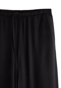Pantaloni sportivi neri con elastico in vita, dettagli con cordino e tasche laterali; texture liscia e design a gamba affusolata.