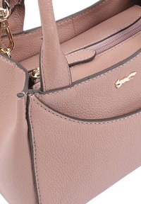 Lichtroze textuur leren handtas met dubbele handvatten, een voorvak, een goudkleurige rits en een klein goudkleurig kattenlogo aan de voorkant.