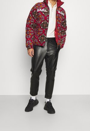 Red patterned puffer jacket with white branding, paired with black leather pants and black sneakers. The design includes various decorative shapes.