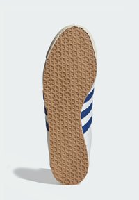 White athletic shoe sole with textured gum rubber, featuring blue stripes and a patterned tread design for enhanced grip.