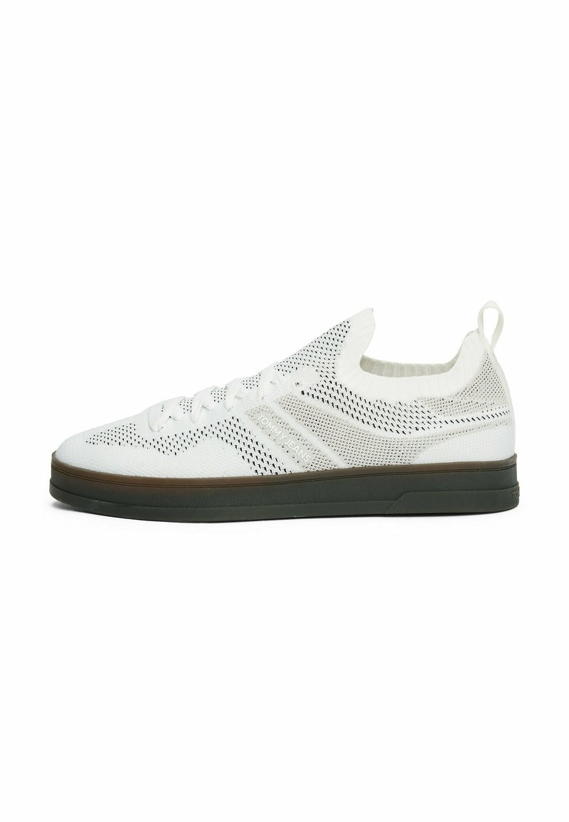 Zapatillas de punto blancas con un diseño transpirable, que presentan un upper texturizado, un cuello elástico y una suela de goma con un acento marrón.