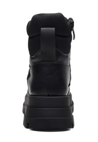 Mustat nilkkurit, joissa on teksturoitu verkkomateriaali yläosassa ja sileä nahkapohja. Tukeva pohja, jossa on selkeä kuviointi ja takaosa, josta voi vetää.