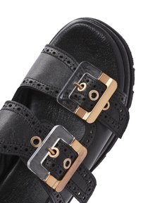 Sandal in pelle nera con due ampiezza di cinturini con dettagli perforati, fibbie decorative in oro e trasparente e suola testurizzata.