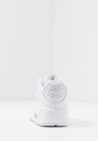 Zapatilla Nike Air blanca con material de cuero, cuello acolchado y talón texturizado con el logo "Nike AIR". Diseño estándar con cordones.